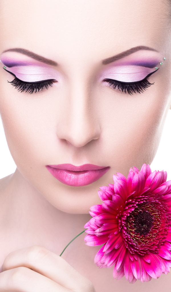 Девушка модель с нежным макияжем с розовым цветком герберы в руке
