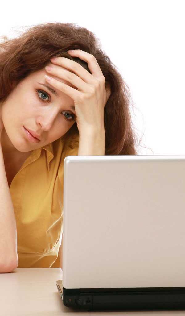 Грустная девушка сидит возле ноутбука 