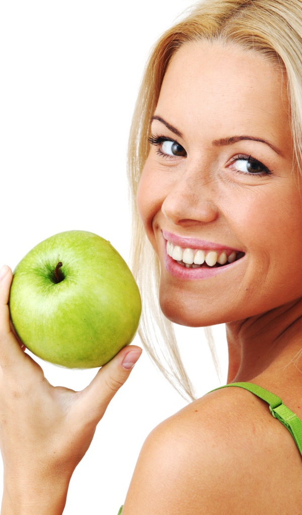 Улыбающаяся девушка блондинка с зеленым яблоком в руке на белом фоне