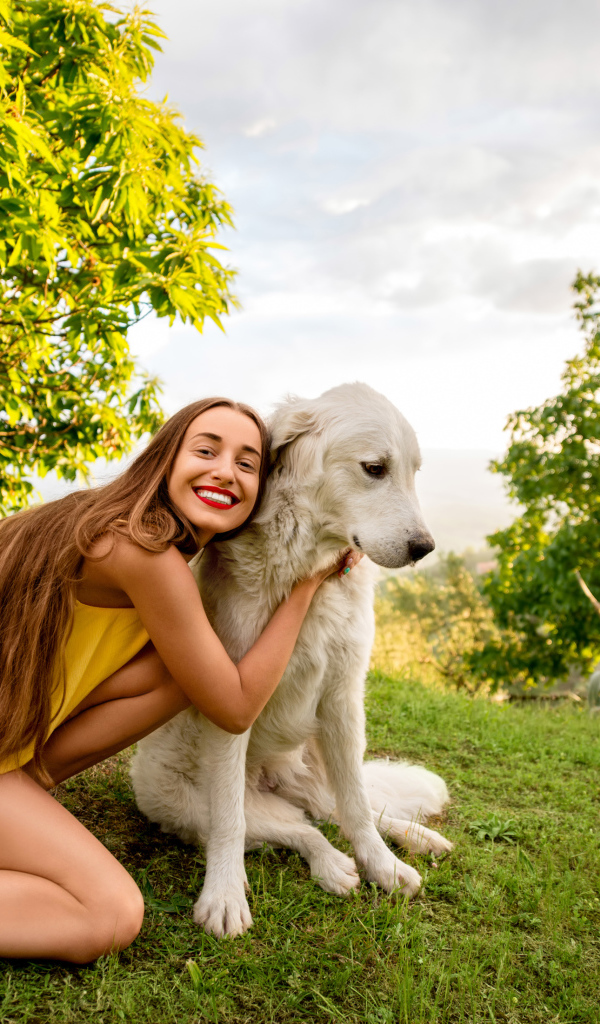 Улыбающаяся шатенка с золотистым ретривером на зеленой траве летом