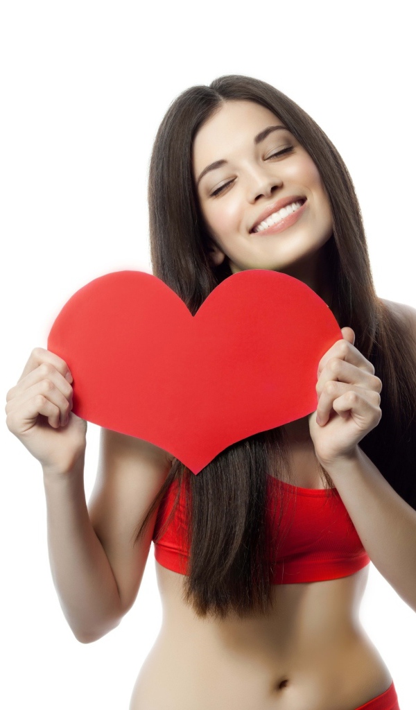 Улыбающаяся брюнетка с красным сердцем в руках на белом фоне