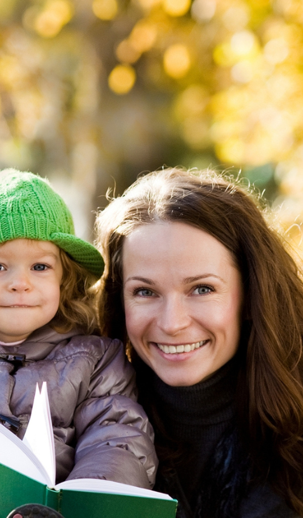 Улыбающаяся девушка с девочкой читают книгу