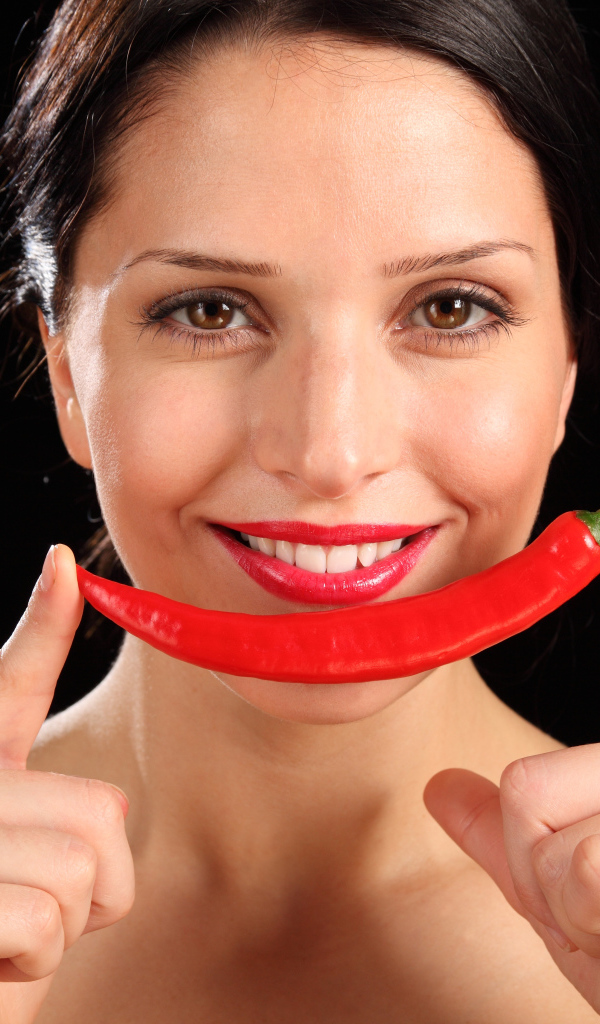 Улыбающаяся девушка с красным перцем на черном фоне