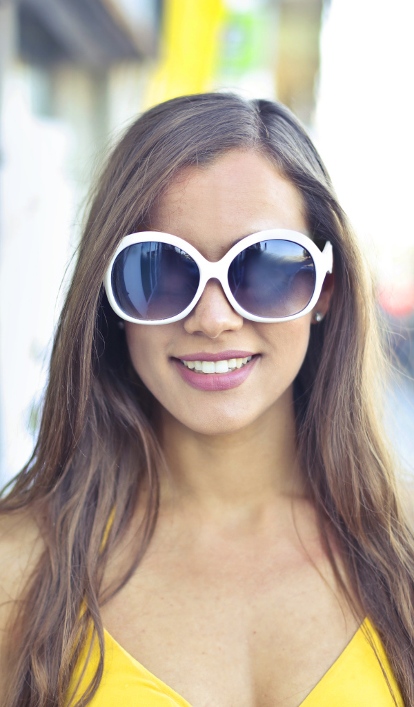 Улыбающаяся молодая девушка в солнечных очках 