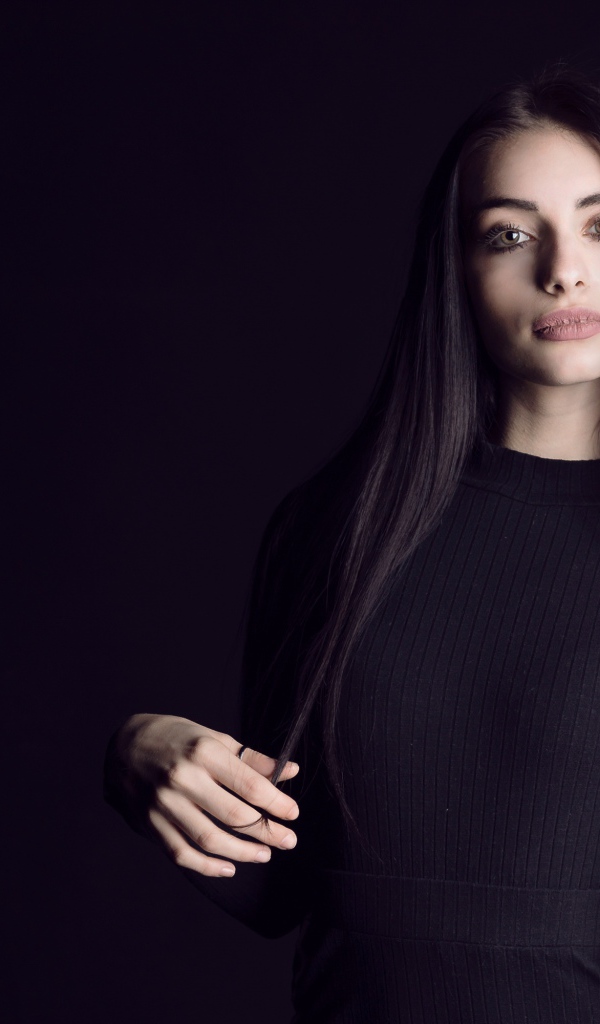 Эффектная брюнетка в черном наряде на черном фоне