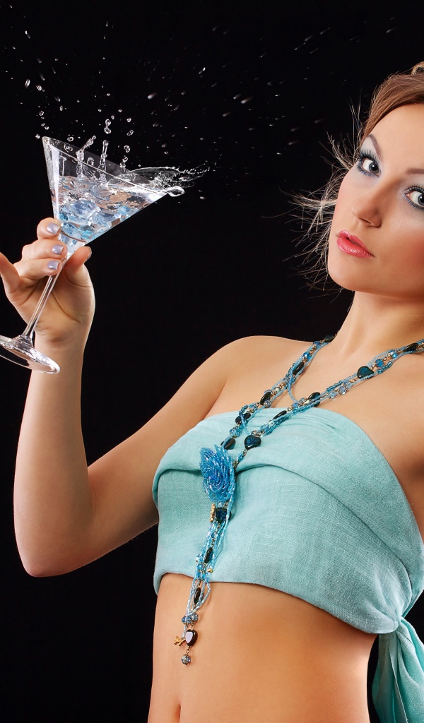 Эффектная молодая девушка с коктейлем в руках на черном фоне