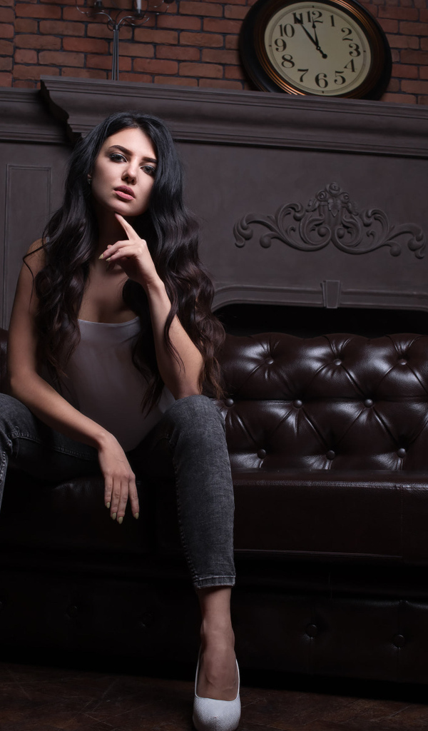 Стильная девушка сидит на кожаном диване