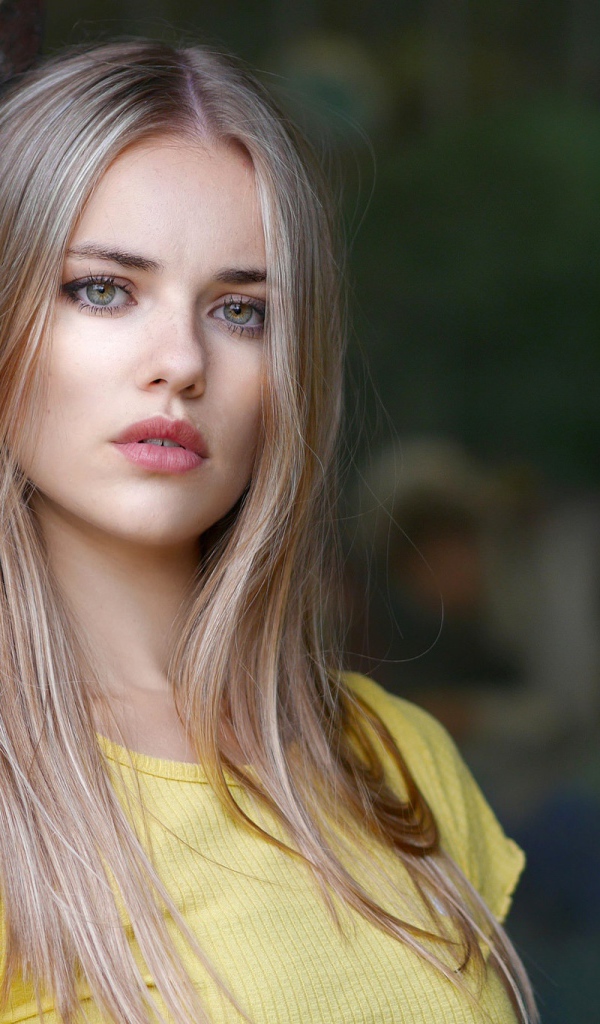 Грустный взгляд красивой светловолосой девушки у стены