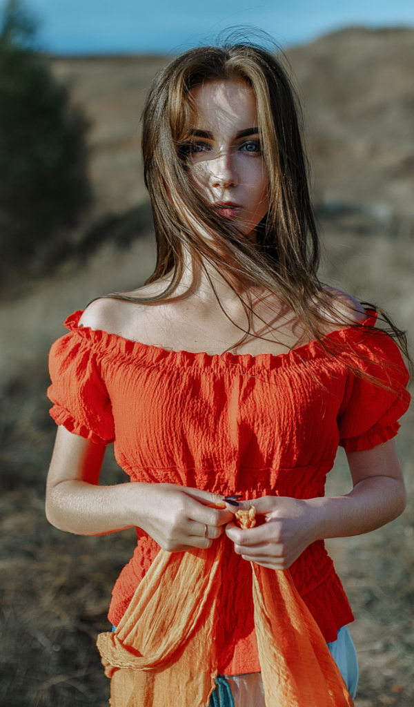 Ветер развивает волосы красивой девушке шатенке 