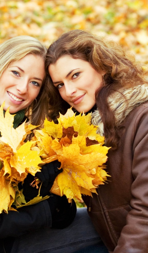 Две красивые девушки с желтыми листьями в руках