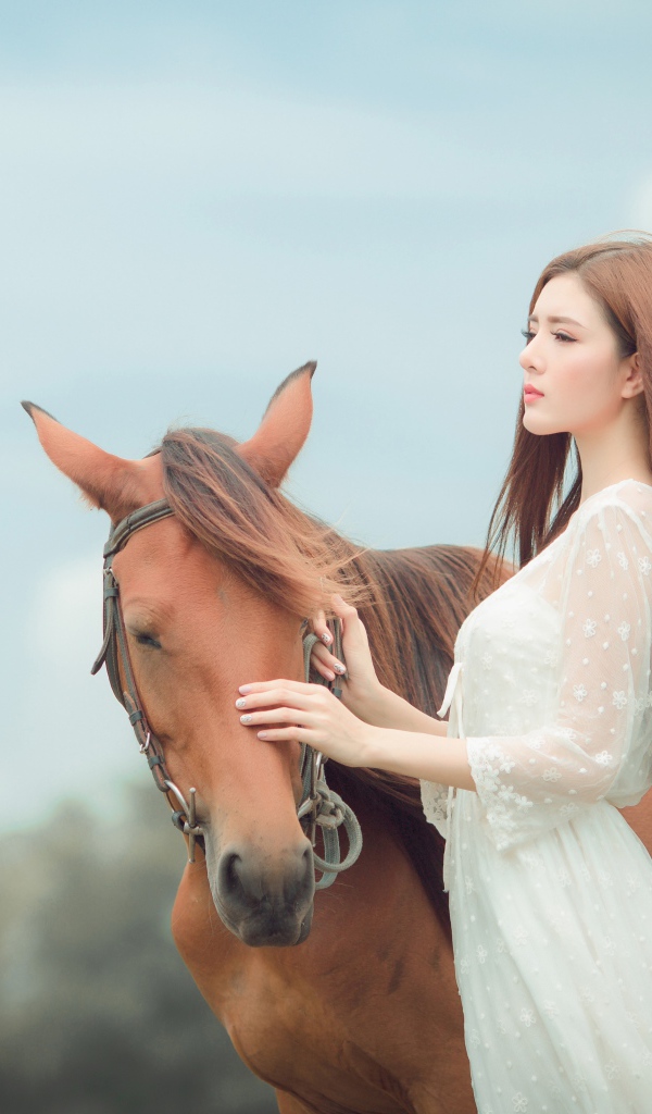 Молодая азиатка в белом платье с лошадью 