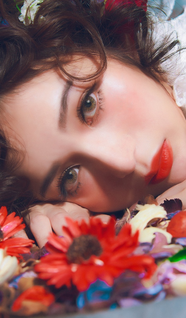 Молодая красивая девушка лежит цветами в волосах