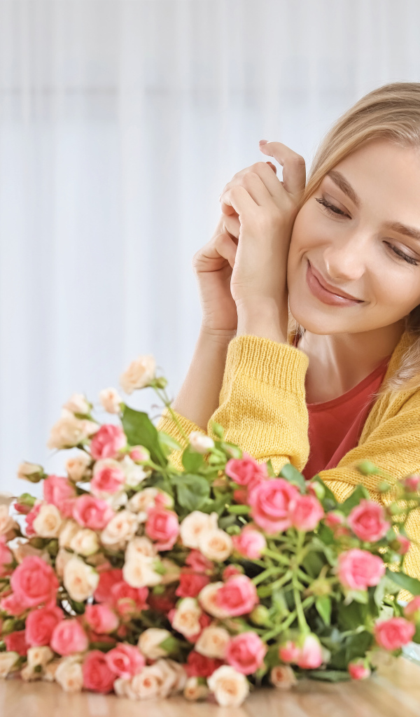 Молодая блондинка с букетом роз на столе