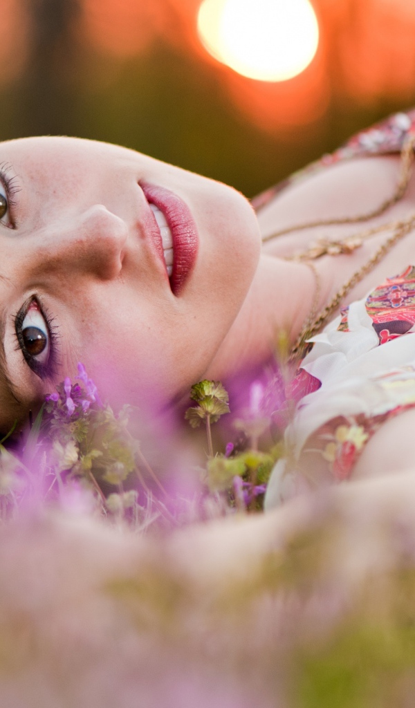 Молодая кареглазая девушка лежит на траве