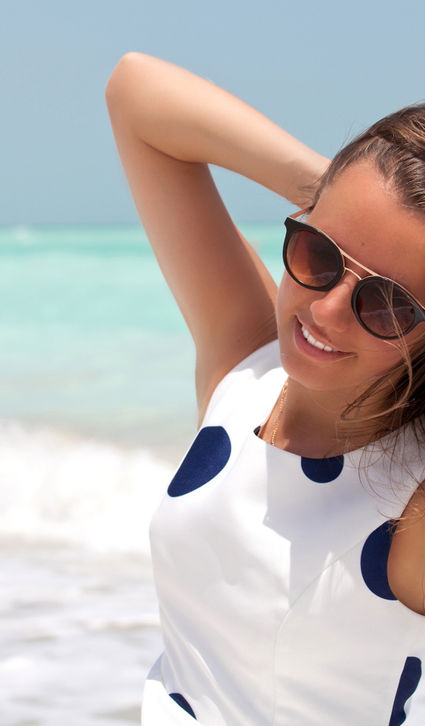 Молодая шатенка в солнечных очках у моря