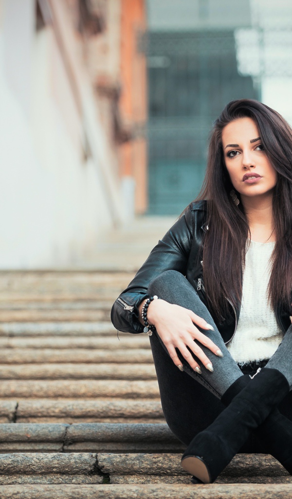 Молодая брюнетка сидит на ступеньках