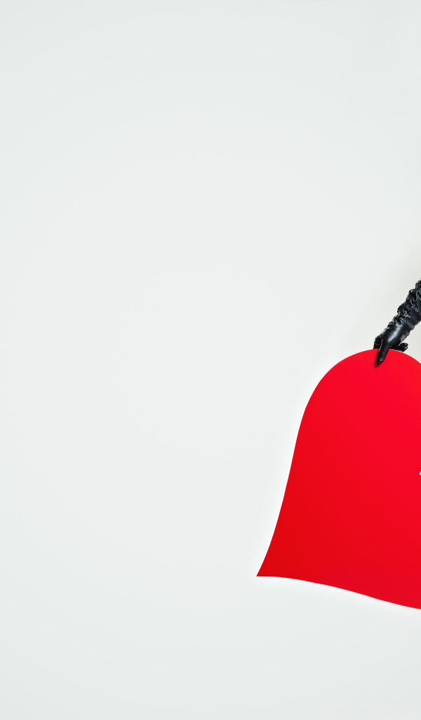 Молодая девушка в черной шляпе с красным сердцем в руке