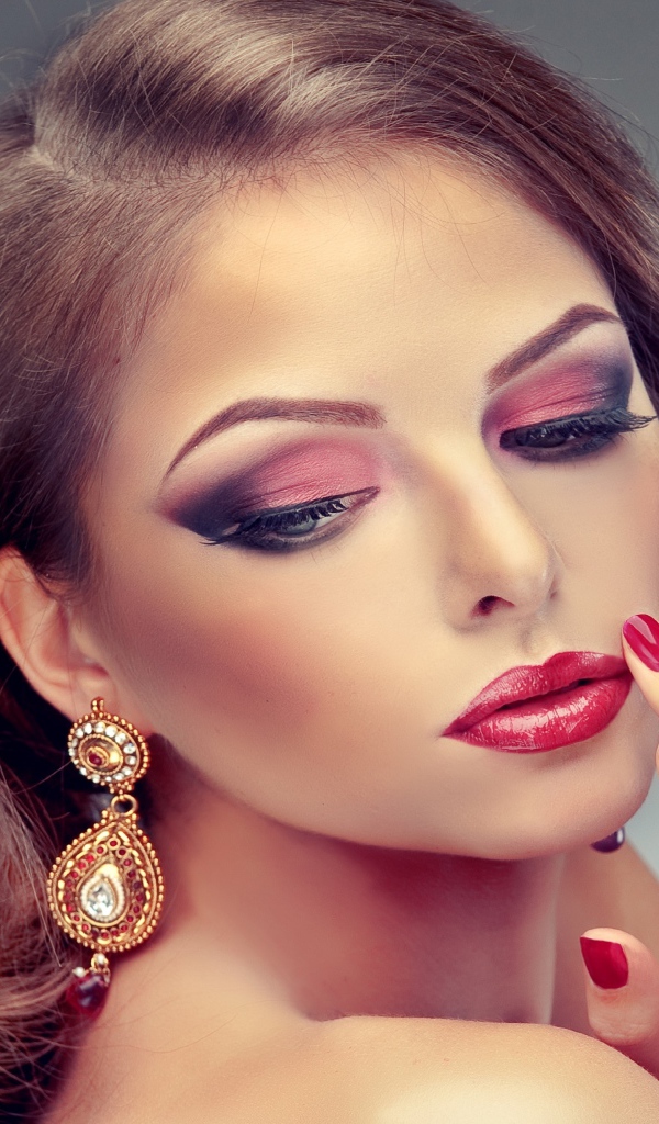 Молодая девушка в ярким макияжем и красными ногтями