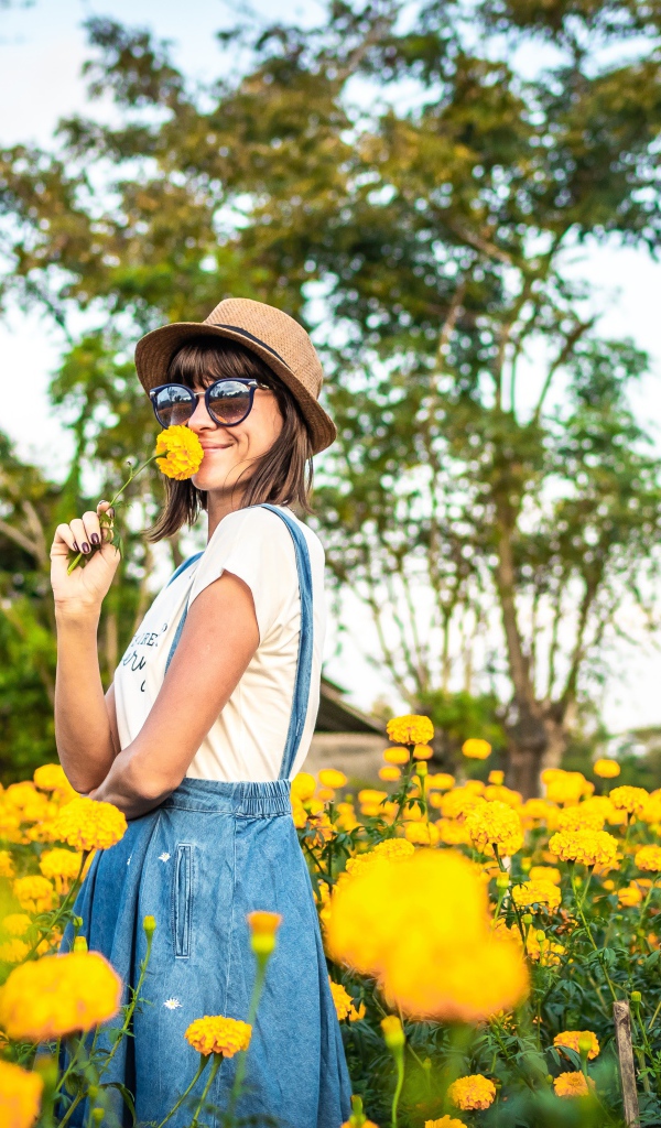 Молодая девушка в солнечных очках в желтых цветах 