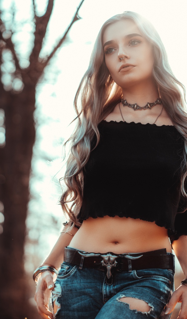 Молодая девушка в рваных джинсах с пирсингом в носу