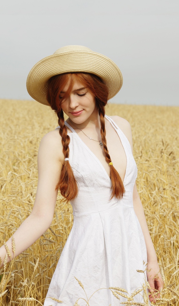 Молодая девушка в белом платье на поле с пшеницей