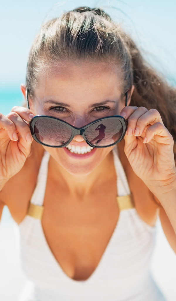 Молодая улыбающаяся девушка в солнечных очках 