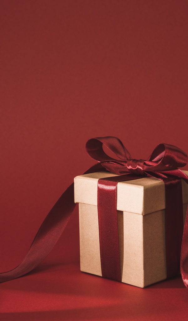 Подарочная коробка с красным бантом на красном фоне