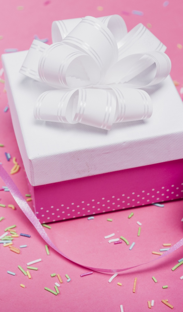 Две подарочные коробки с бантами на розовом фоне