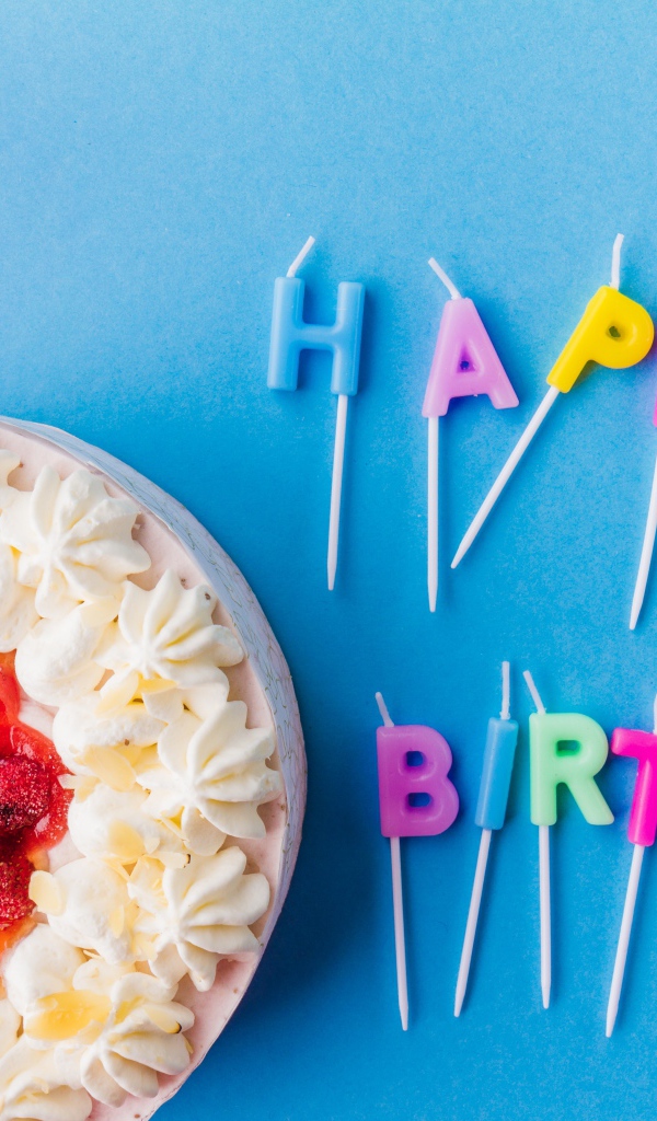 Красивый торт с кремом и клубникой на голубом фоне со свечами на день рождения