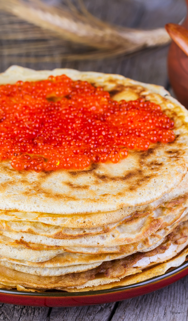 Стопка блинов с красной икрой на деревянном столе угощение на Масленицу