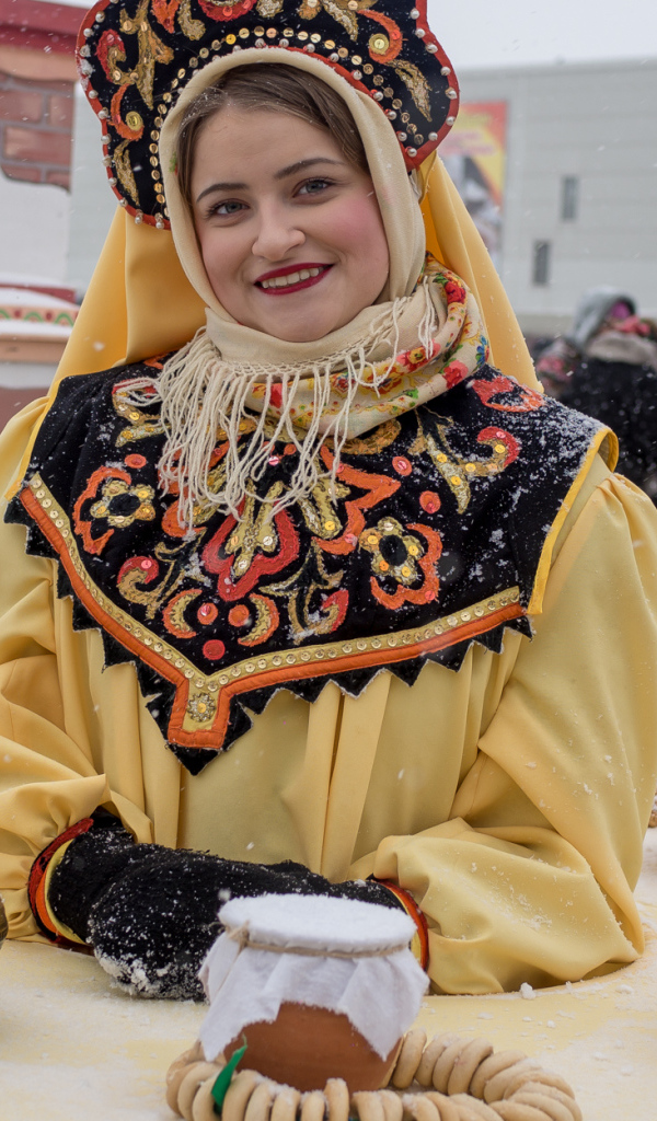 Красивая молодая девушка с угощениями на Масленицу 2018