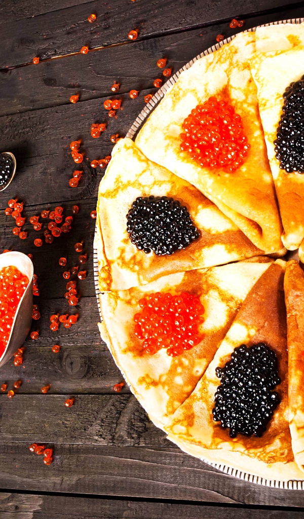 Блины с черной и красной икрой на деревянном столе на Масленицу