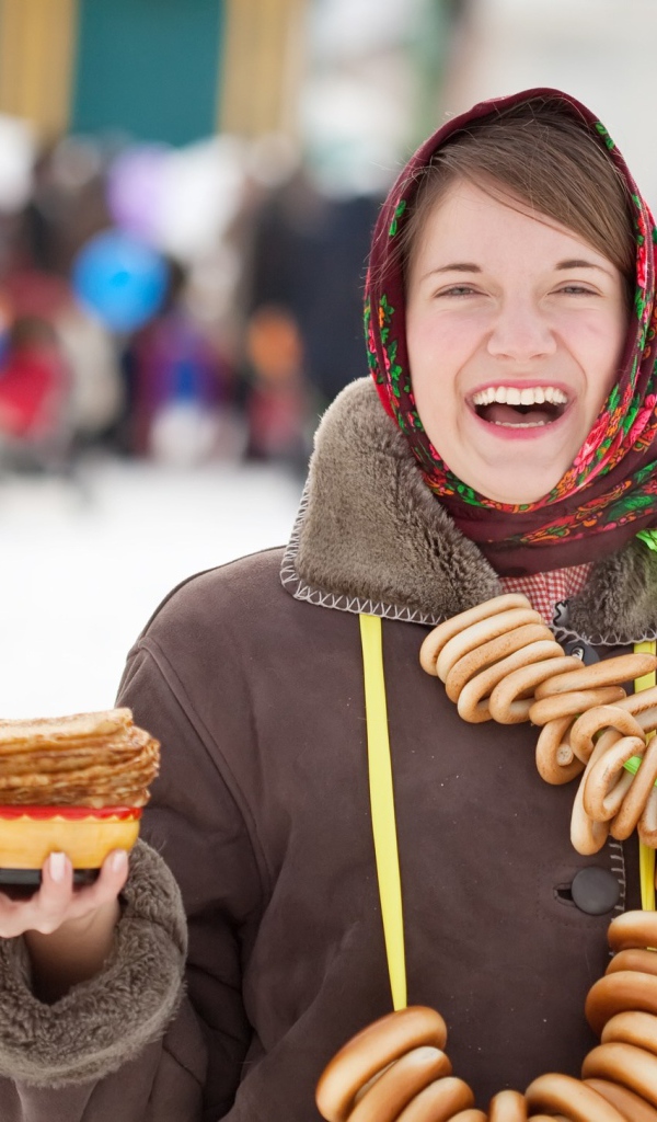 Улыбающаяся девушка с угощениями на праздник Масленица 2018