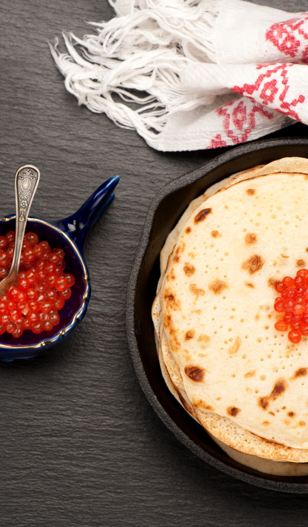 Тонкие блины с красной икрой на столе вид сверху