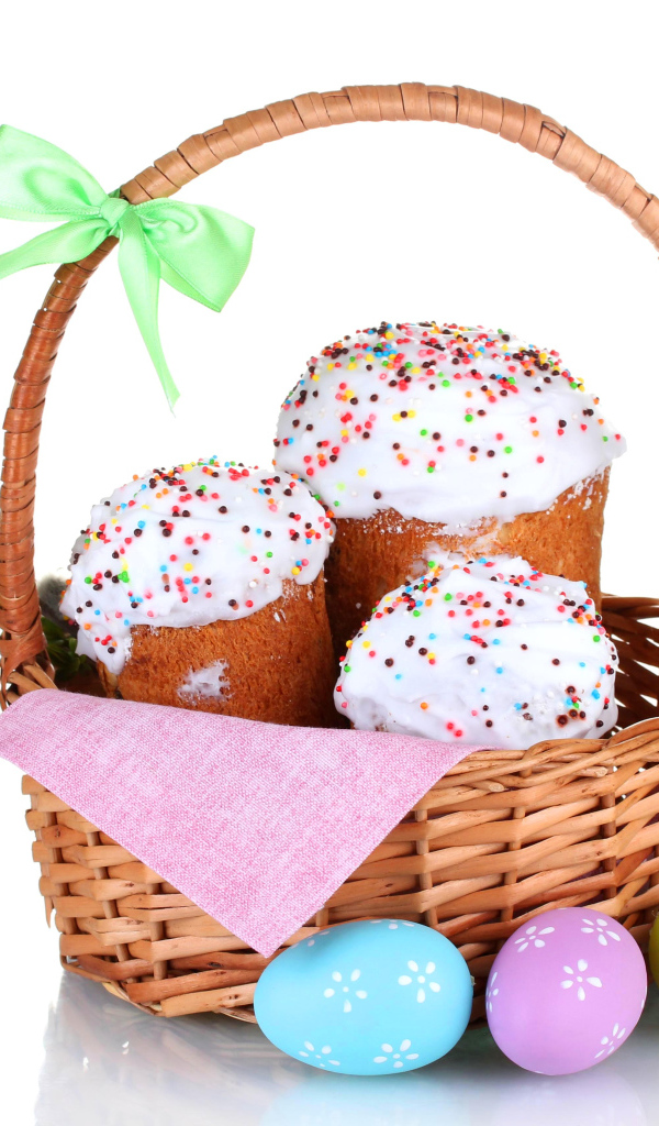 Пасхальные куличи в корзине с крашеными яйцами на белом фоне