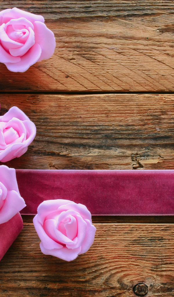 Восьмерка из ленты с розовыми розами на деревянном фоне на Международный женский день