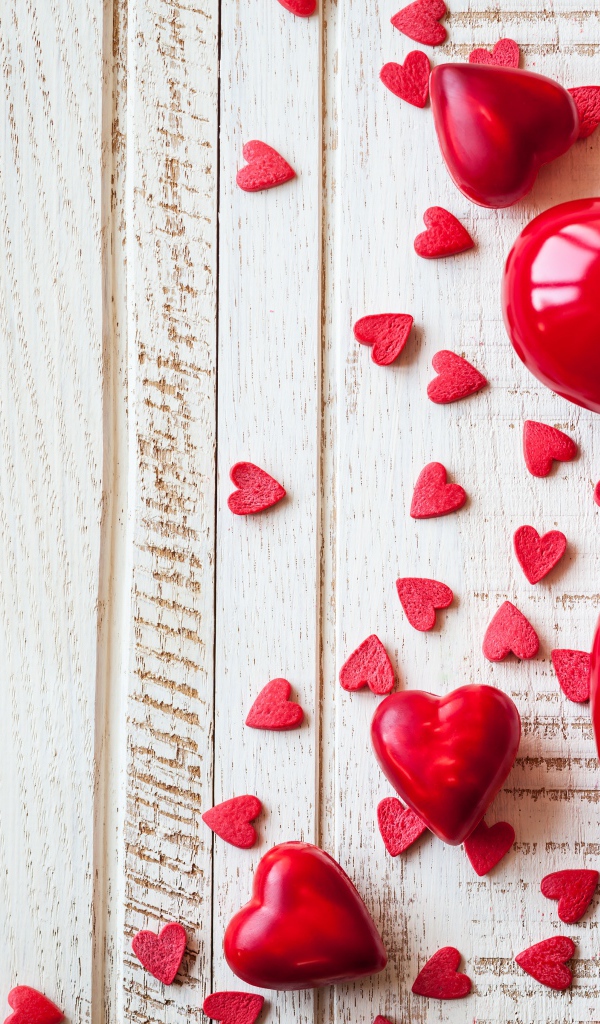 Большие и маленькие  красные  сердечки на деревянном фоне