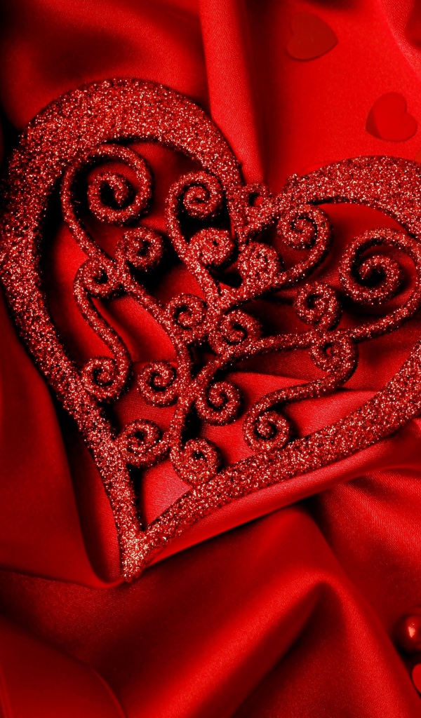 Блестящее сердце на красной атласной ткани 