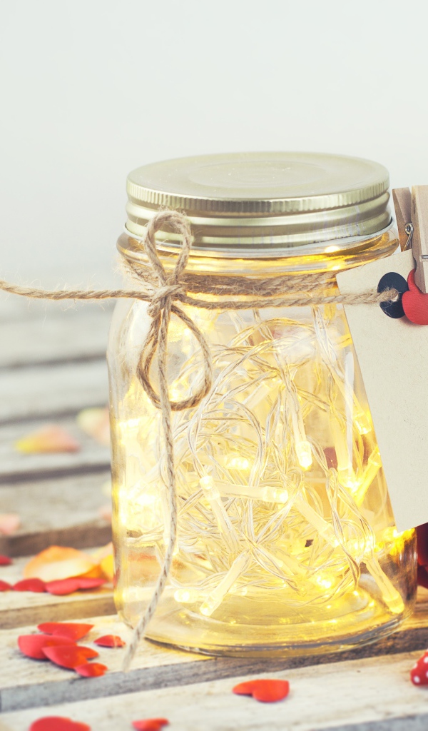 Стеклянная банка с гирляндой на столе с букетом роз и сердечками