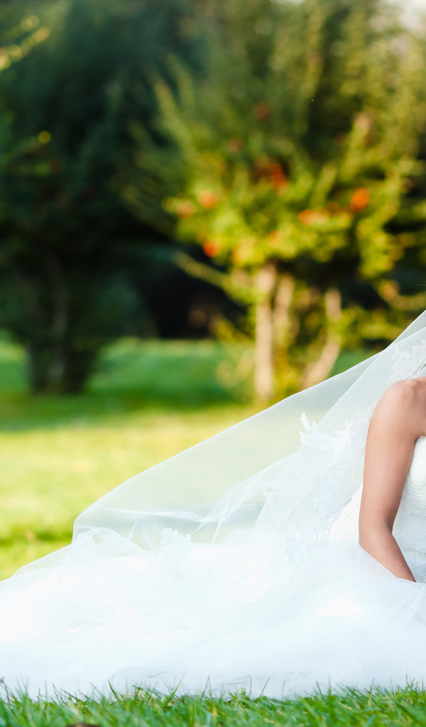 Счастливые жених и невеста сидят на зеленой траве