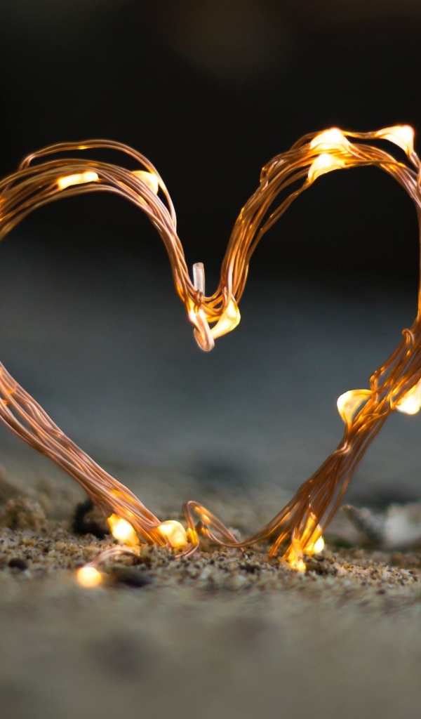 Сердце из гирлянды на песке