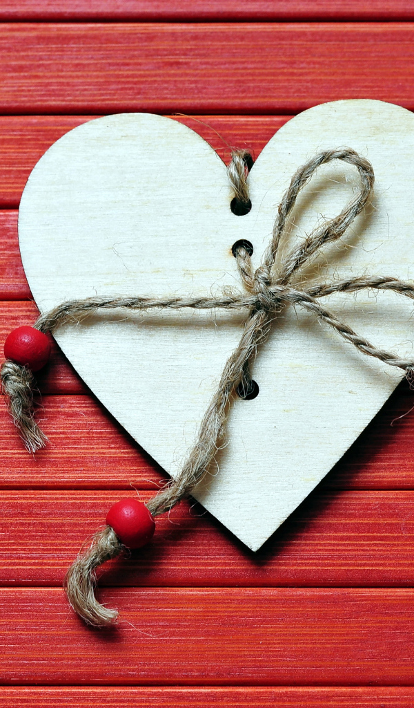 Сердце с веревкой на красном деревянном фоне