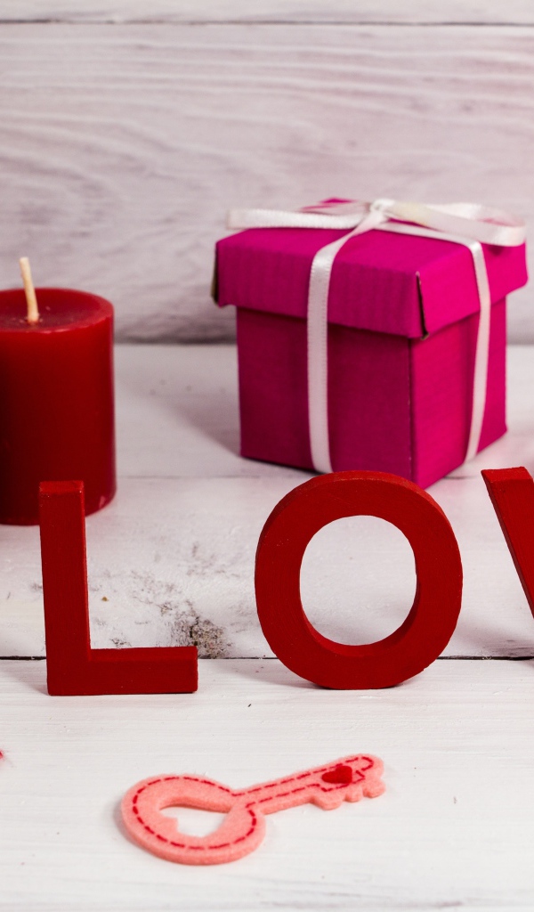 Надпись любовь на столе с красными свечами и подарком