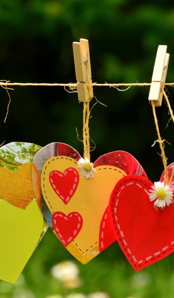 Бумажные сердечки висят на веревке на прищепках