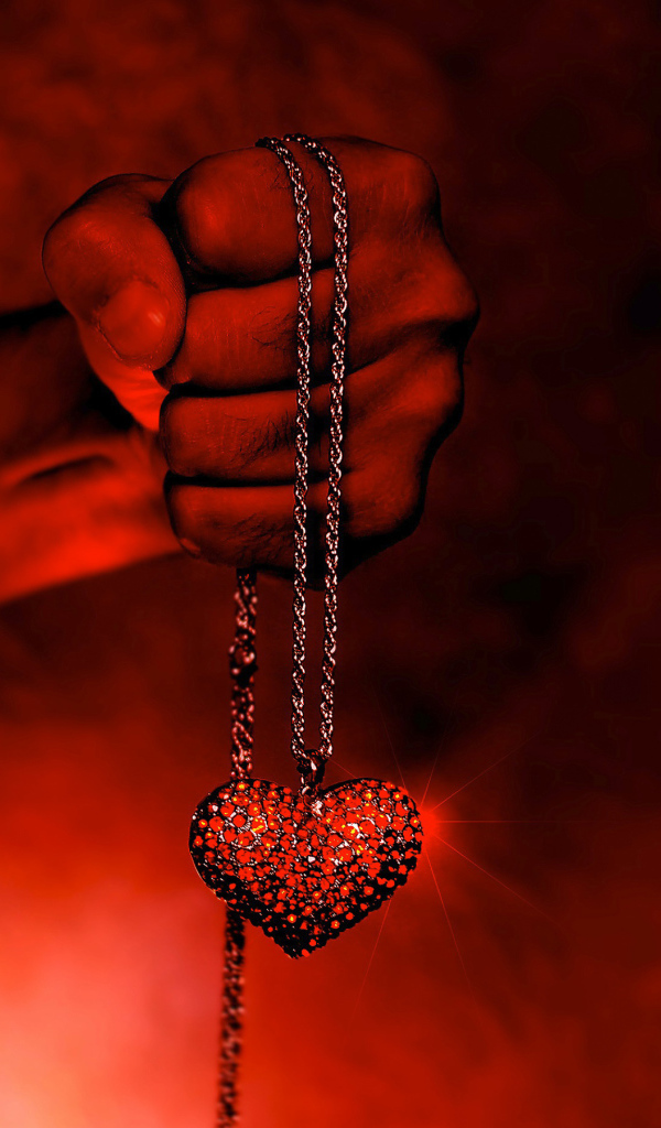 Pendant with a heart on a chain in a man's hand
