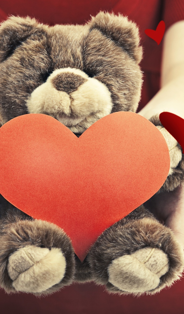 Плюшевый медведь с большим красным сердцем в руках