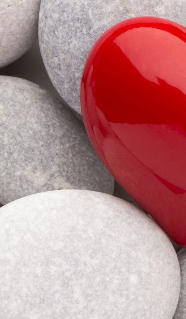 Красное сердце лежит на серых камнях 
