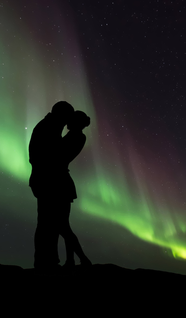 Силуэт влюбленной пары на фоне северного сияния 