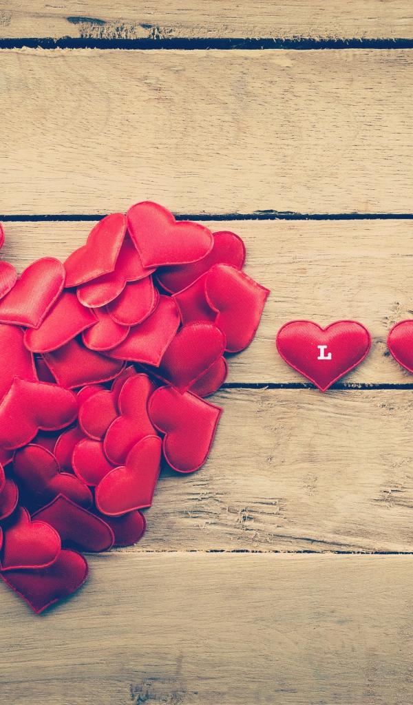 Маленькие красные сердечки на деревянной поверхности 