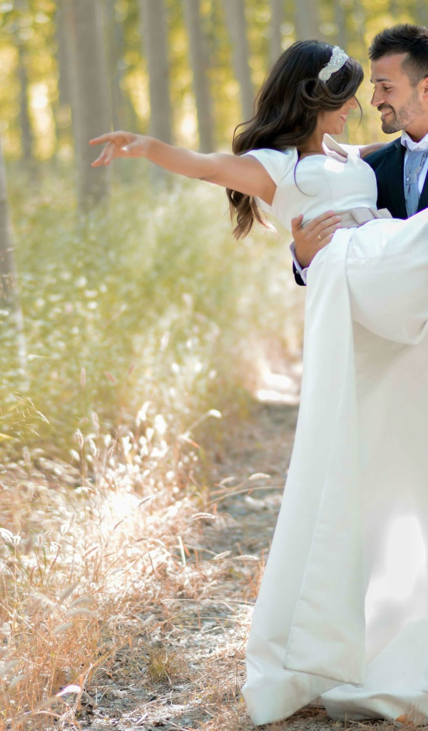 Парень жених держит на руках невесту в белом платье